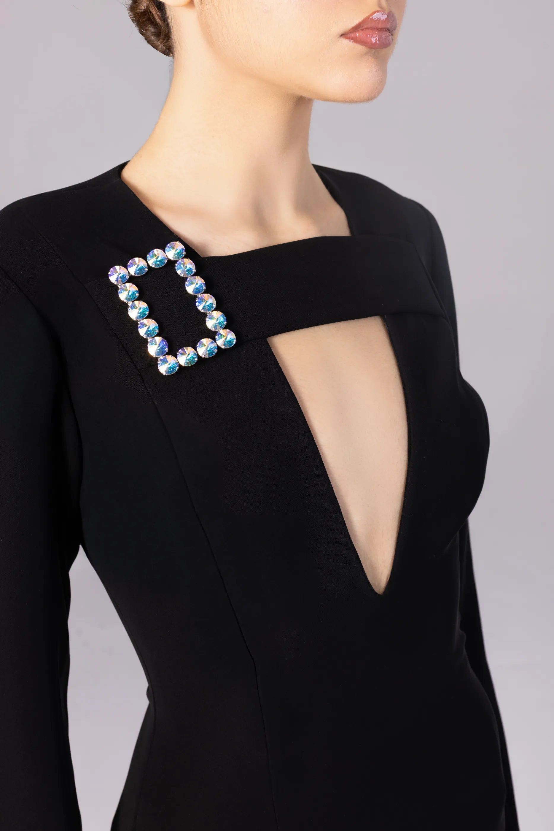 Black dress with a unique brooch design on a plain background